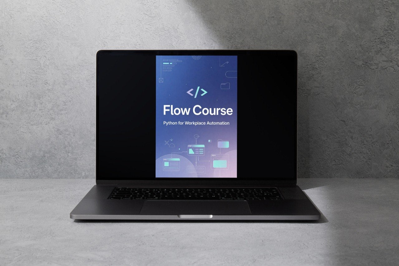 A dark gray laptop sits open on a gray surface against a textured gray wall, with its screen displaying a course graphic that reads 'Flow Course' and 'Python for Workplace Automation'.